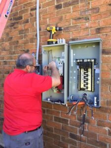 An electrician working on an outdoor electrical panel and meter box for Mr. Electric of Montgomery County Alabama in Montgomery, AL.