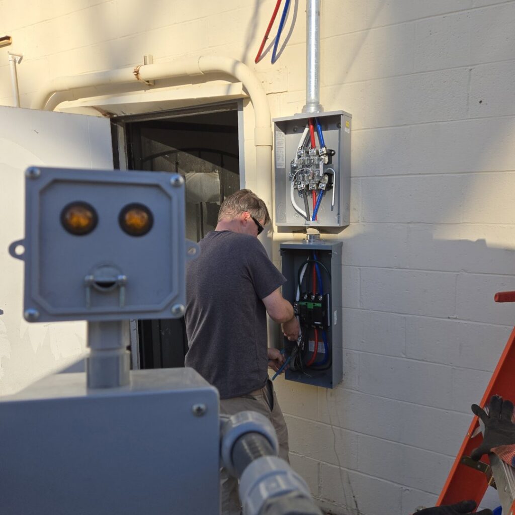 An electrician from The Wire Guy working on an outdoor electrical panel in San Jose, CA.