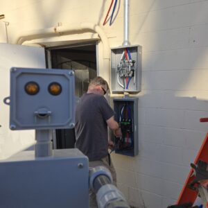 An electrician from The Wire Guy working on an outdoor electrical panel in San Jose, CA.
