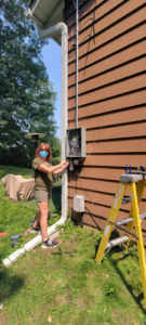 An electrician working on an outdoor electrical meter box on a house in Woodbury, MN, by John Kivel Electric, LLC.