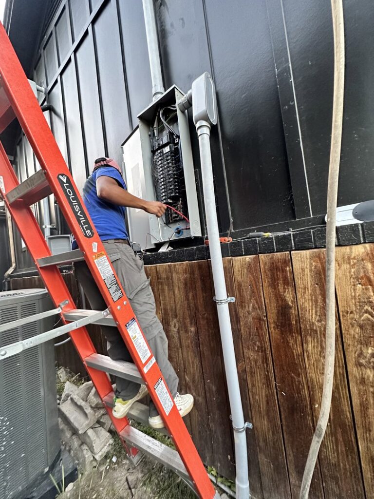 An electrician on a ladder performing work on an outdoor electrical panel for Babcock Electric & Communications in Lake Charles, LA.