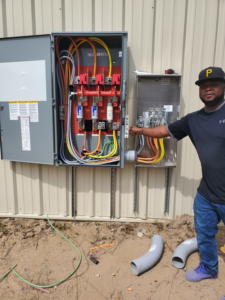 An electrician working on an outdoor electrical panel installation for Overton Power Solutions Electric in Hephzibah, GA