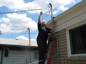 An electrician from Mac Electric Company working on overhead electrical wires and a service mast in Warren, MI.