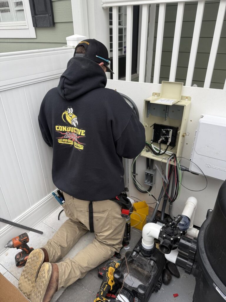 An electrician from Conductive Electrical Contracting working on pool equipment wiring in Smyrna, DE.