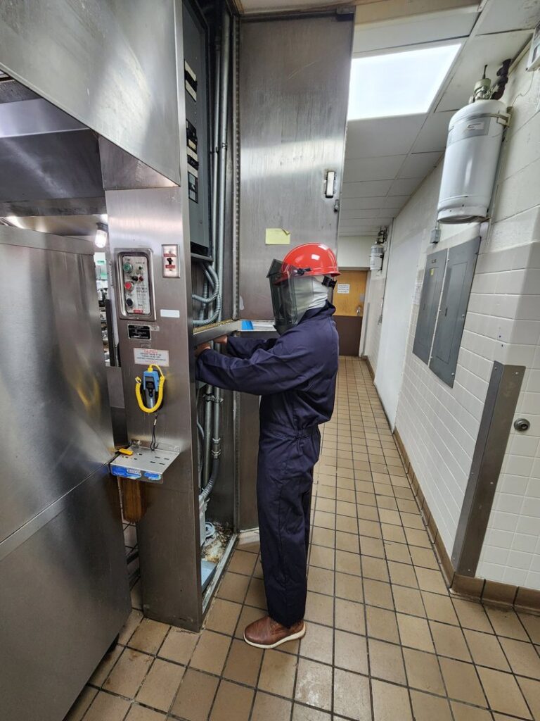 An electrician in full personal protective equipment working on an electrical panel for ALC Electric LLC in Goose Creek, SC