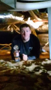 An electrician working under a house in a crawl space for Kavanagh Electric in Fresno, CA.