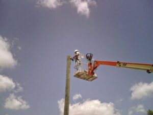 An electrician in a bucket lift performing work on a utility pole for Argosy Electric, Inc. in Newport News, VA
