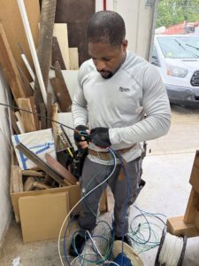 An electrician from Green Volt Electric LLC working with electrical wires, stripping and connecting them in Durham, NC.
