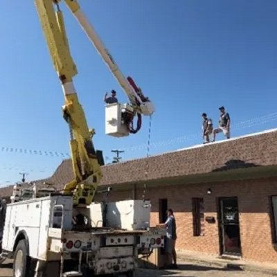 Electricians using a bucket truck for commercial electrical work on a building by Brian Jackson Electrical Service LLC in Sadler, TX