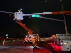 Electricians in a bucket truck working on overhead electrical lines at night for Vierregger Electric Co. in Omaha, NE.
