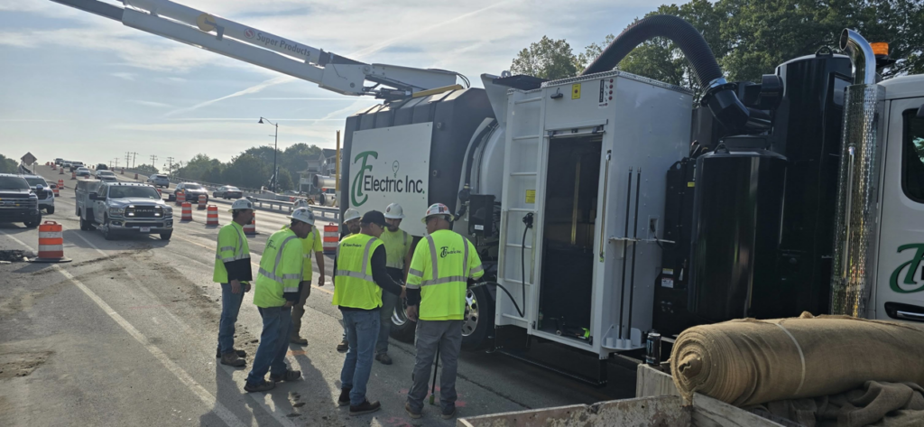 A crew of electricians and a vacuum excavator truck working on a road construction site for TC Electric, Inc in Indianapolis, IN.