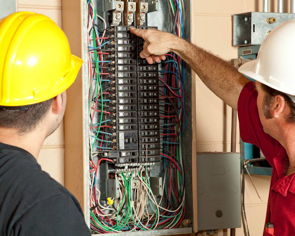 Two electricians from Lewis Electric inspecting an open electrical breaker box in Macon, GA