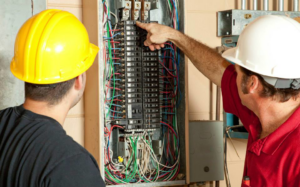 Two electricians inspecting a circuit breaker panel for T-Volt, Inc. Electrical Contractor in Fort Lauderdale, FL.