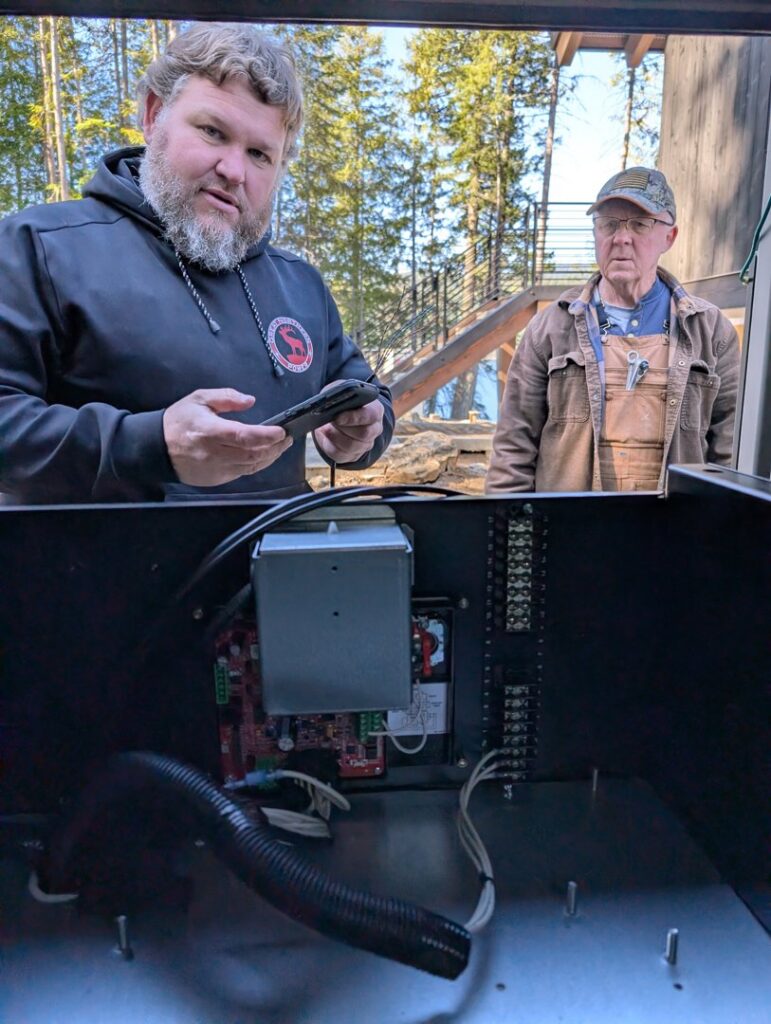 Two electricians inspecting an open generator control box for Great Northern Power in Kalispell, MT.