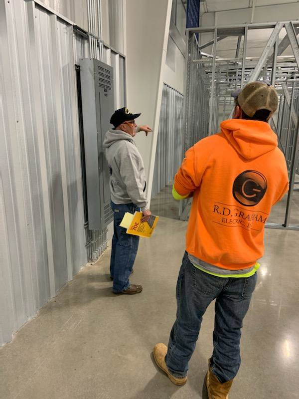 Electricians inspecting an electrical panel and conduit installation at a job site for RD Graham Electric, LLC in Greensboro, NC.