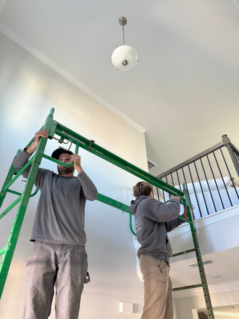 Electricians from Weiss Electric LLC installing a ceiling light fixture using scaffolding in Saint Charles, MO.