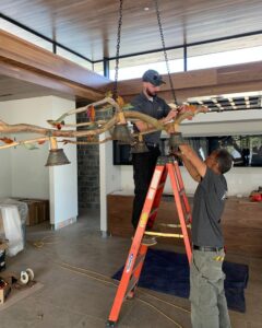 Two electricians from Coffin Electric installing a large decorative chandelier in Grimes, IA.
