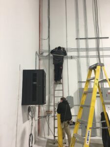Two electricians installing electrical conduit and wiring on a commercial wall, demonstrating work by RHS Electrical Services in Westerville, OH.