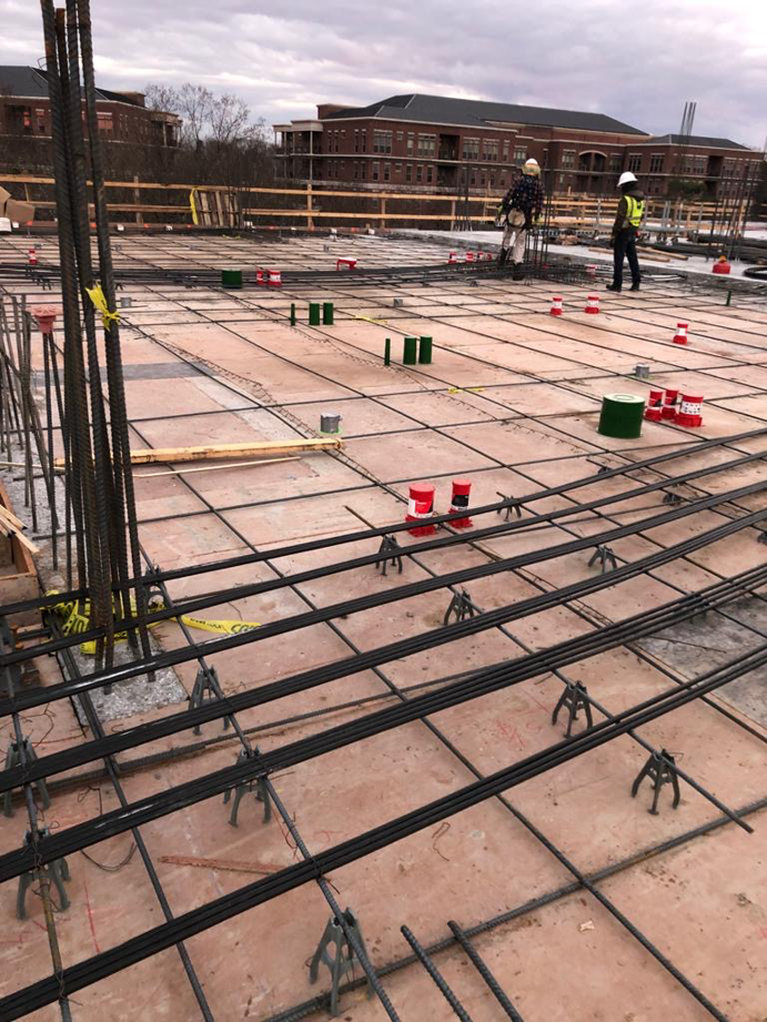 Electricians installing red and green conduits on a construction site with rebar and concrete forms for MVL Electric, LLC in Atlanta, GA