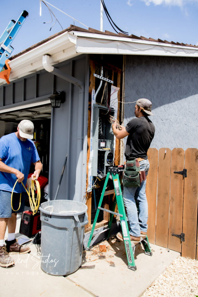 Two electricians from Smith Electrical Contractors, Inc. installing an exterior electrical panel in El Cajon, CA.