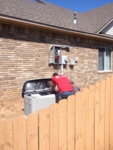 Two electricians from Corley Electric & Automatic Power Solutions installing a Generac generator in Fort Smith, AR.
