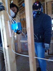 Two electricians installing in-wall wiring during new construction for The Specialist Electrical Contractor in Albuquerque, NM.