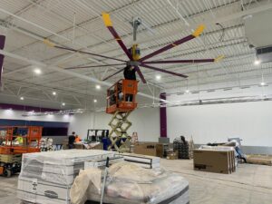 Electricians installing a large industrial fan from a scissor lift at a commercial site by Pro 1 Electric, Inc. in Parkersburg, WV