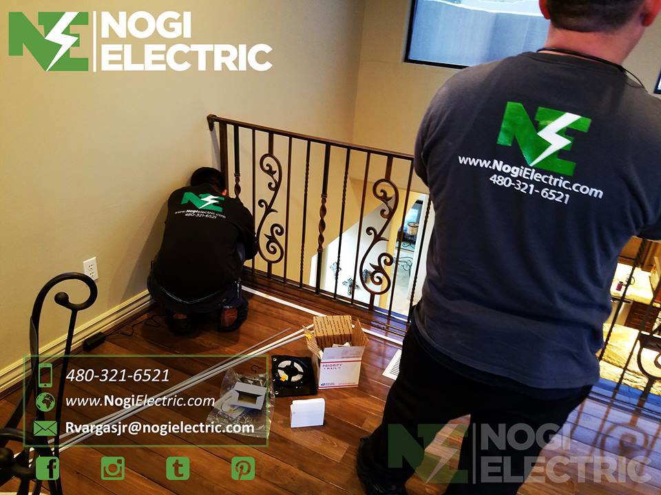 Electricians from Nogi Electric LLC installing lighting or electrical components near a staircase in Mesa, AZ.