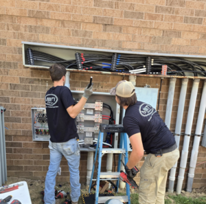 Two electricians installing an outdoor electrical panel and conduit system for Monty Enterprises in Canton, OH.
