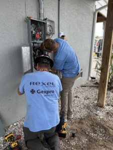 Electricians installing an outdoor electrical panel for Sound Electric LLC in Saint James City, FL.