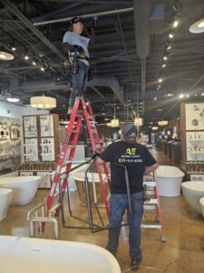 Two electricians from Acevedo's Electric installing overhead wiring and conduit in a commercial space in Dallas, TX.
