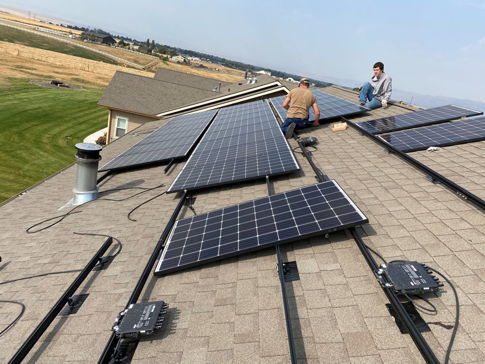 Two electricians installing solar panels on a residential roof for J C Electric & Solar in Lewiston, ID