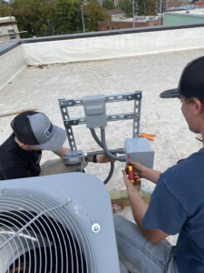 Two electricians from Redmond Electric LLC installing rooftop HVAC electrical wiring and conduit in Horn Lake, MS.
