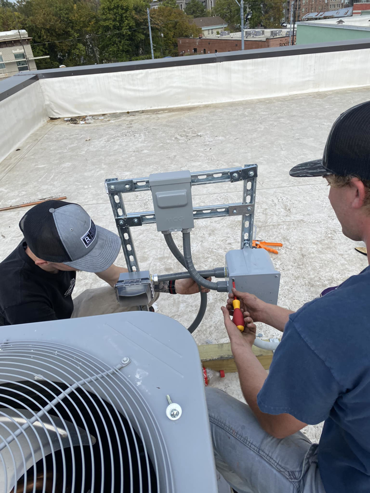 Two electricians from Redmond Electric LLC installing rooftop HVAC electrical wiring and conduit in Horn Lake, MS.