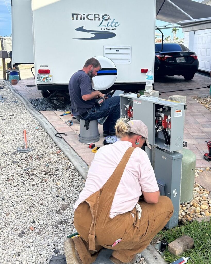 Electricians installing an RV electrical hookup at a campsite for Sound Electric LLC in Saint James City, FL.