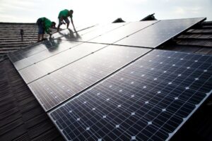 Two electricians from Alternate Energy Inc. installing solar panels on a residential roof in Pearl City, HI.