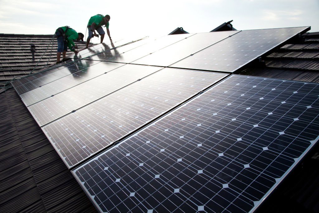 Two electricians from Alternate Energy Inc. installing solar panels on a residential roof in Pearl City, HI.