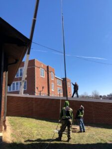 Electricians installing a tall pole with a crane at a commercial site by Pro 1 Electric, Inc. in Parkersburg, WV