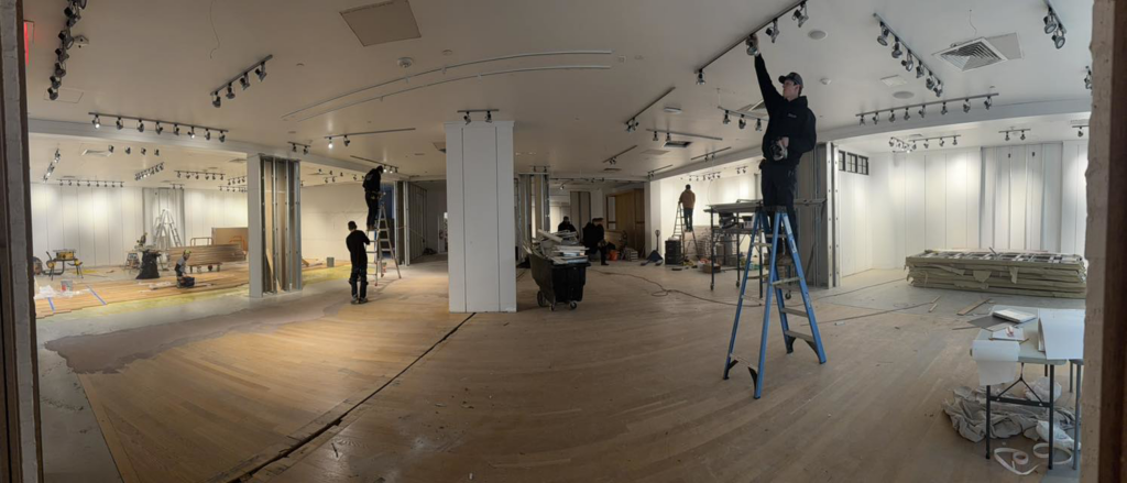 Electricians installing track lighting in a large commercial space by Power Tech Electrical Services in Durham, NC.