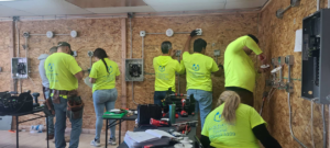 Electricians installing electrical wiring and panels on a wooden wall at Millan Electric Service llc in Las Vegas, NV