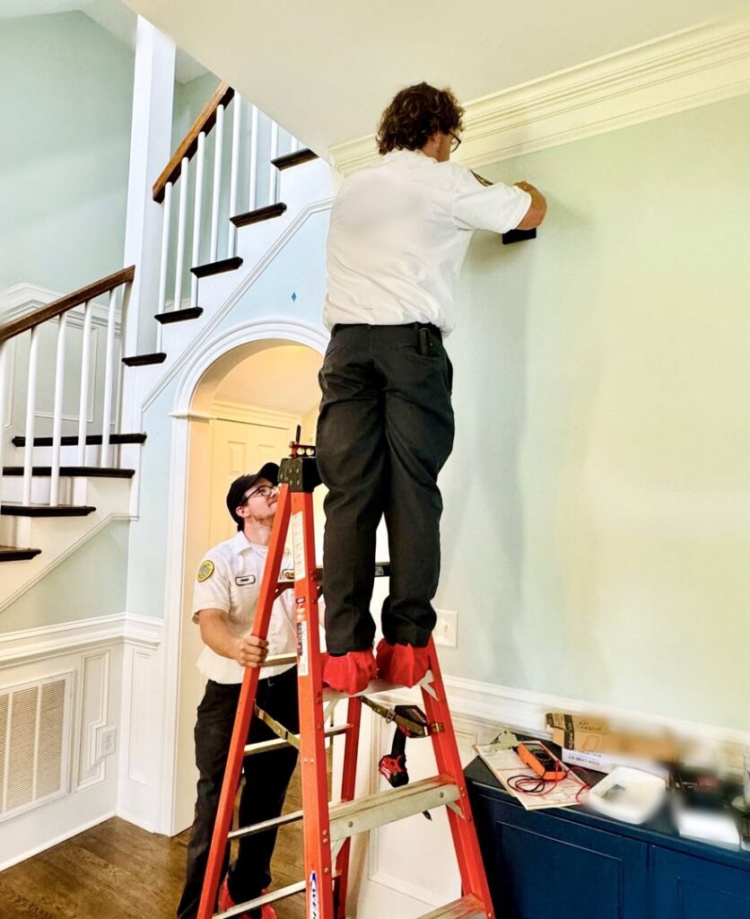 Two electricians from Mister Sparky of Columbia installing wiring on a wall in a home in West Columbia, SC.