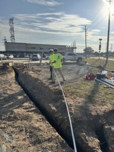 Electricians from Big City Lighting and Electric laying electrical conduit in a trench in Houston, TX.