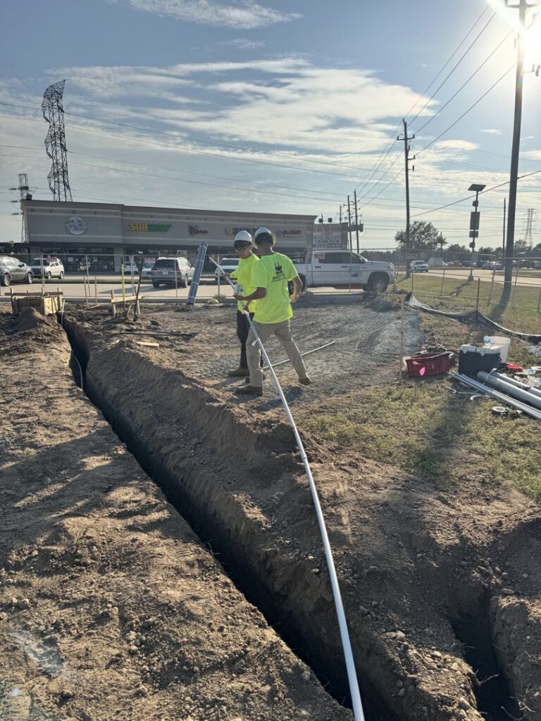 Electricians from Big City Lighting and Electric laying electrical conduit in a trench in Houston, TX.