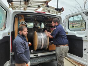 Two electricians loading large spools of electrical cable into a work van for Sherrill Company, LLC Electrical Contractors in Columbus, GA.