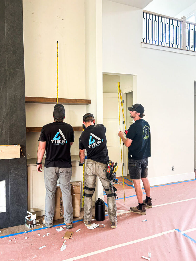 Electricians from Tier 1 Electric measuring a wall for electrical installation in a new construction in Boise, ID.