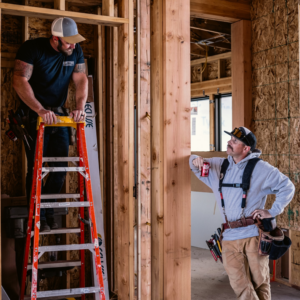 Two electricians working on a ladder at a construction site for Hometown Electric in Delta, CO.