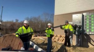 Electricians pulling large electrical cables from a spool to a building by Pro 1 Electric, Inc. in Parkersburg, WV