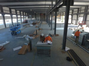 Electricians from Brase Electrical Contracting Corp reviewing blueprints on a large commercial construction site in Omaha, NE.