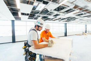 Two electricians from Brase Electrical Contracting Corp reviewing electrical plans on a commercial construction site in Omaha, NE.
