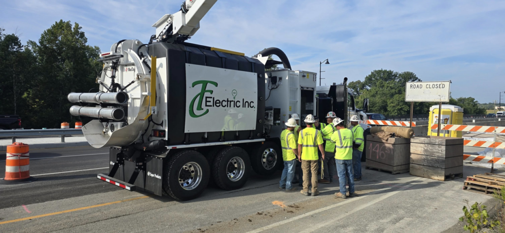 Electricians and a vacuum excavator truck performing utility work on a road construction site for TC Electric, Inc in Indianapolis, IN.